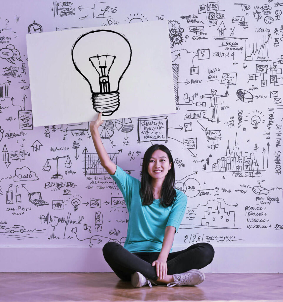 Auf dem Bild ist eine Frau, mit einem Bild von einer Glühbirne in der Hand. Das soll unsere Implementierungsstrategien für S/4HANA Projekt darstellen.