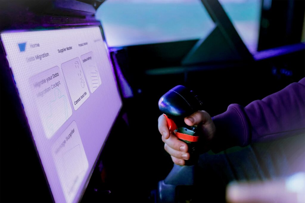 Ein Flugzeugcockpit von dem ein Display und der Steuerknüppel zu sehen ist. Auf dem Display ist ei stilisiertiertes SAP Migrations Cockpit zu sehen. Am Steuerknüppel greift eine Hand, die das Flugzeug steuert. Die Person trägt einen violetten Eubuleus Hoodie. 